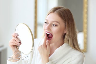 young woman looking at her teeth in a mirror