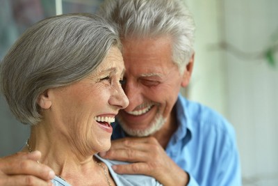 mature couple laugh and embrace while spending time outside