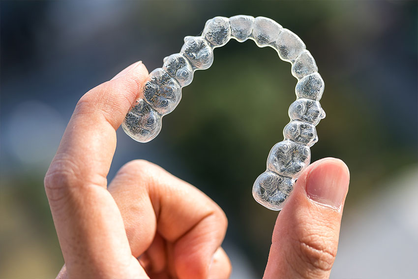 hand holding up an Invisalign clear retainer
