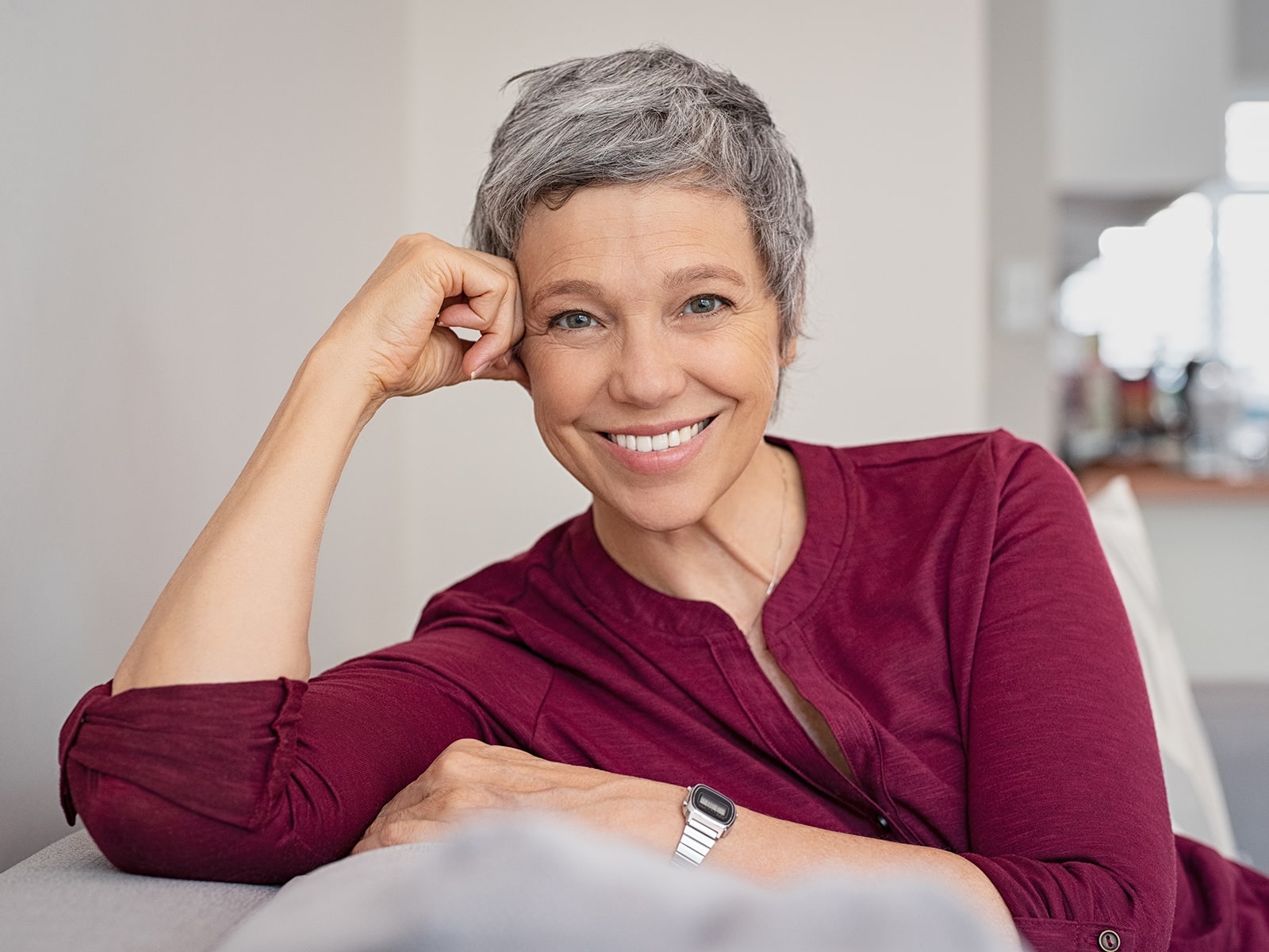 Elderly woman smiling head on hand-min Elderly woman smiling head on hand