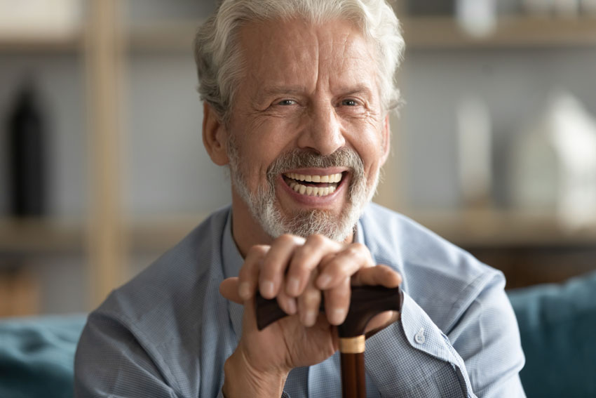 senior man with All-on-4 smiling and leaning on a cane