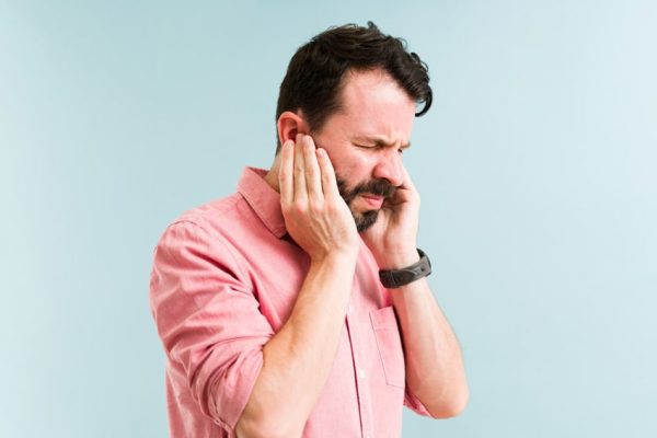 mature adult man holding his jaw and ears in pain