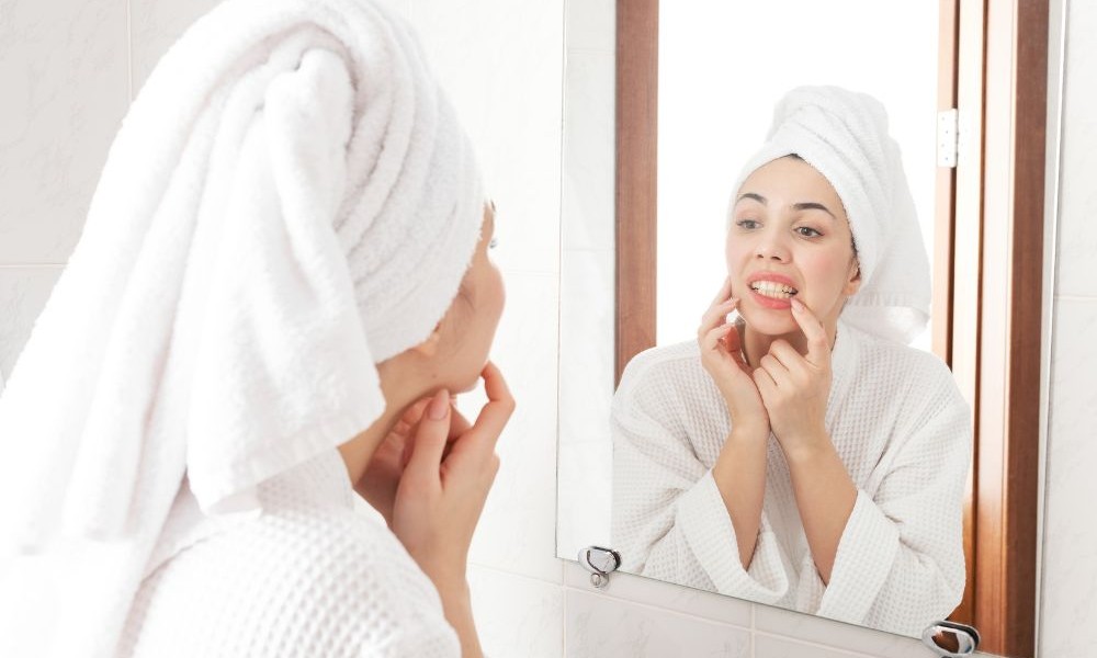 Woman looking at teeth in mirror woman with towel around hair looking at teeth in mirror