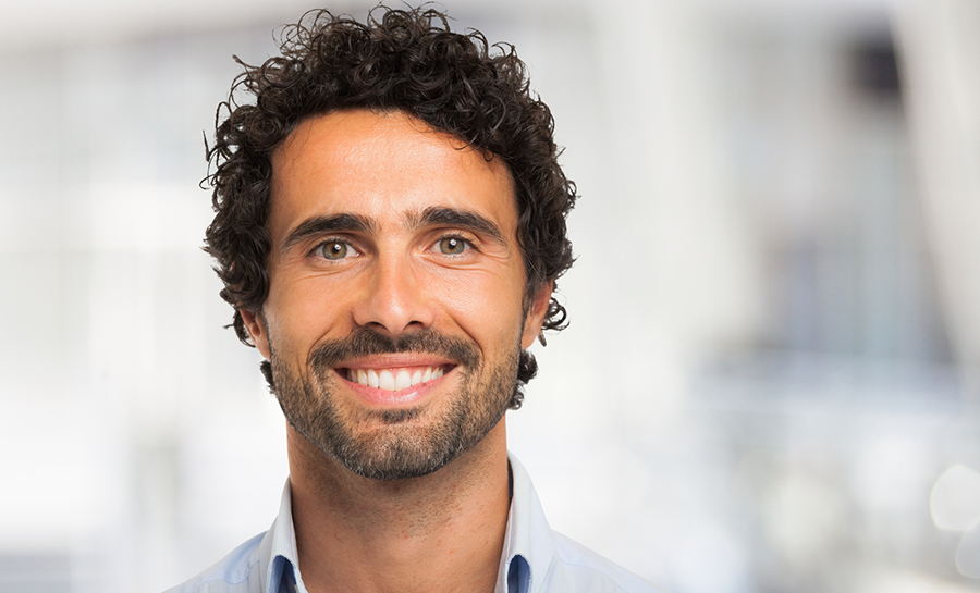 man with short curly hair shows off his healthy smile